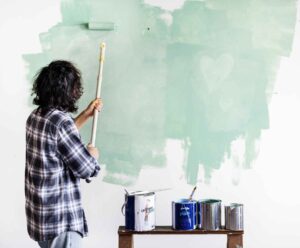 A person paints a wall light green, showing McCandless Plumbing & Excavation can help with home upgrades and inspections.