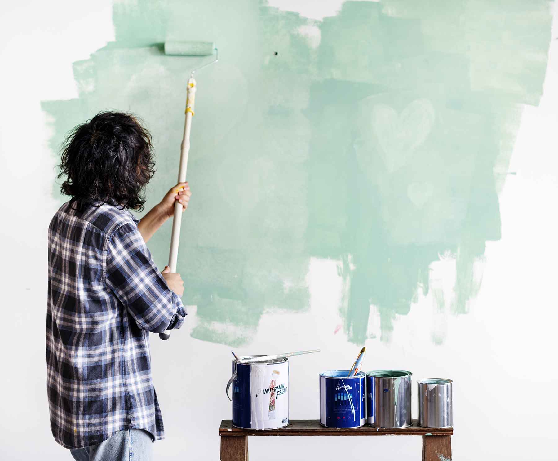 A person paints a wall light green, showing McCandless Plumbing & Excavation can help with home upgrades and inspections.