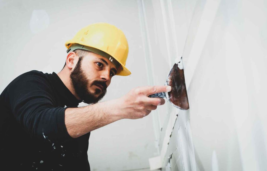 A McCandless Plumbing & Excavation worker carefully repairs a wall, showing the care and skill needed for sewer repair jobs.