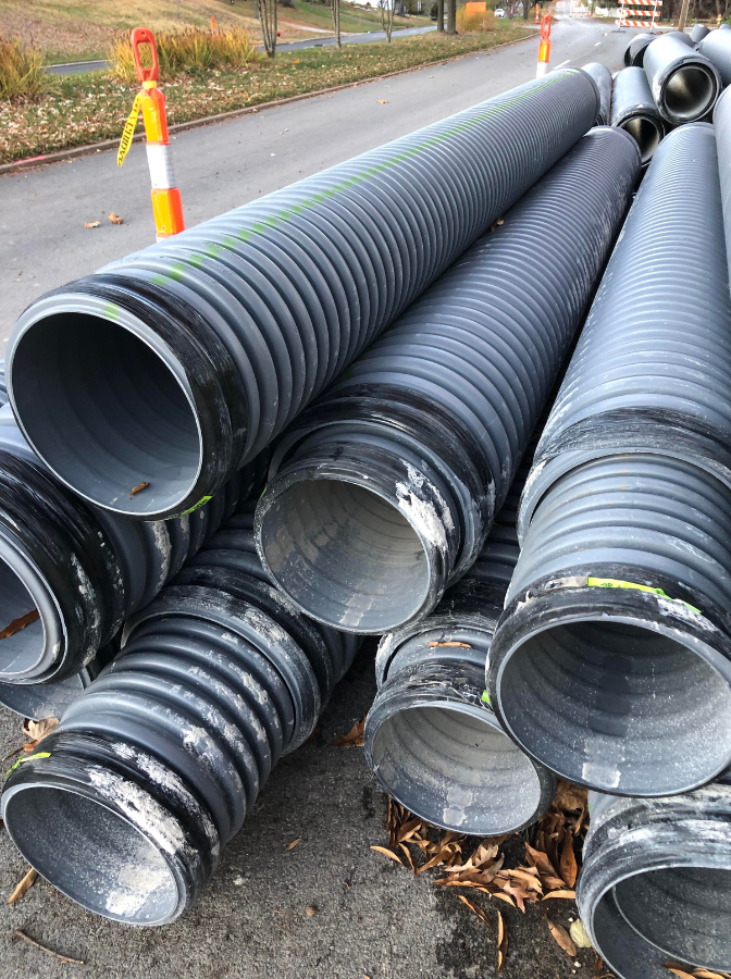 McCandless Plumbing & Excavation works on street pipe repairs, with signs of inspection and safety cones present.