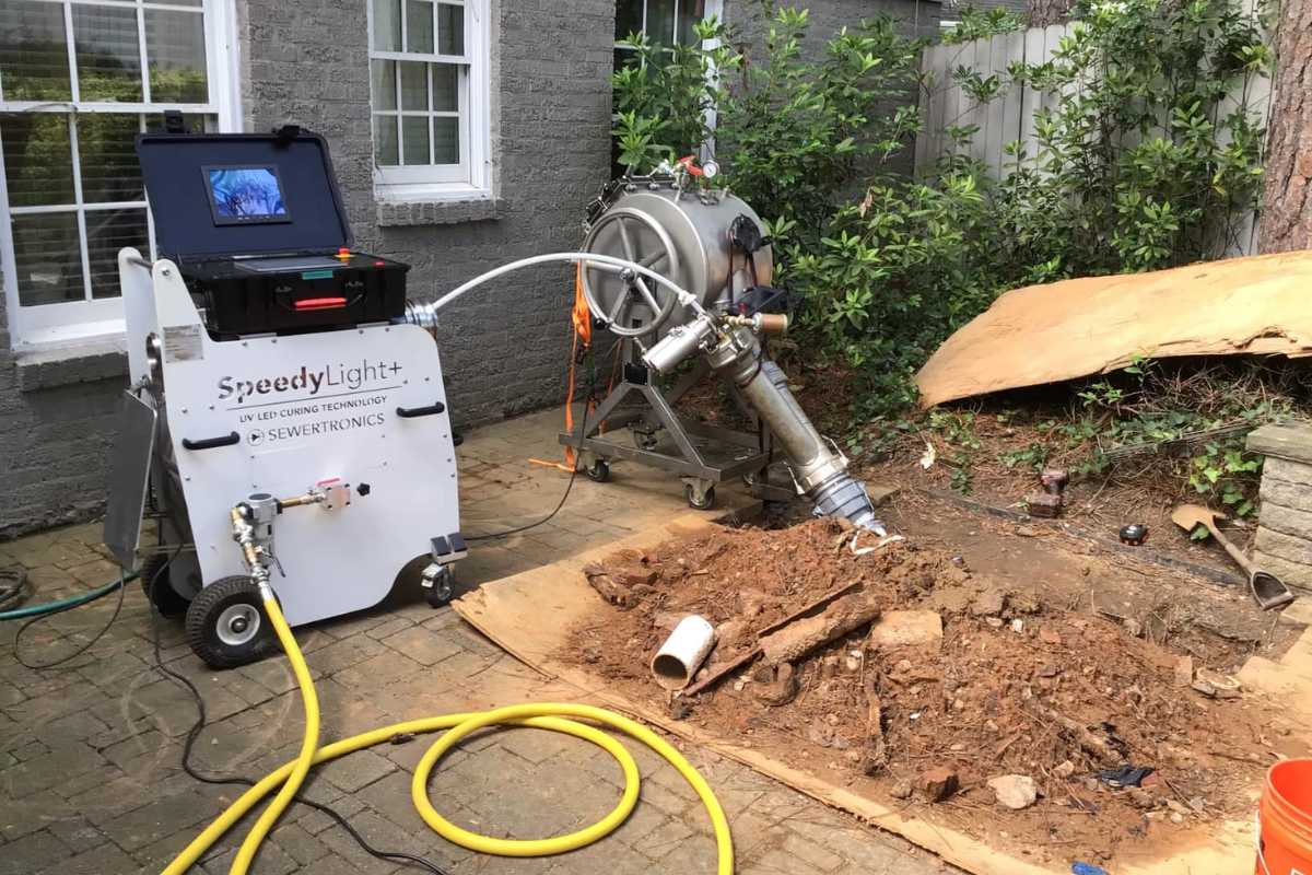 McCandless Plumbing & Excavation using trenchless equipment to fix a sewer pipe, with a screen showing the pipe's condition.