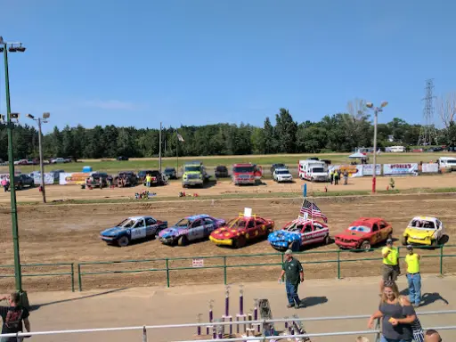 People gather at a McCandless Plumbing & Excavation outdoor event with colorful cars and a fun, lively atmosphere.