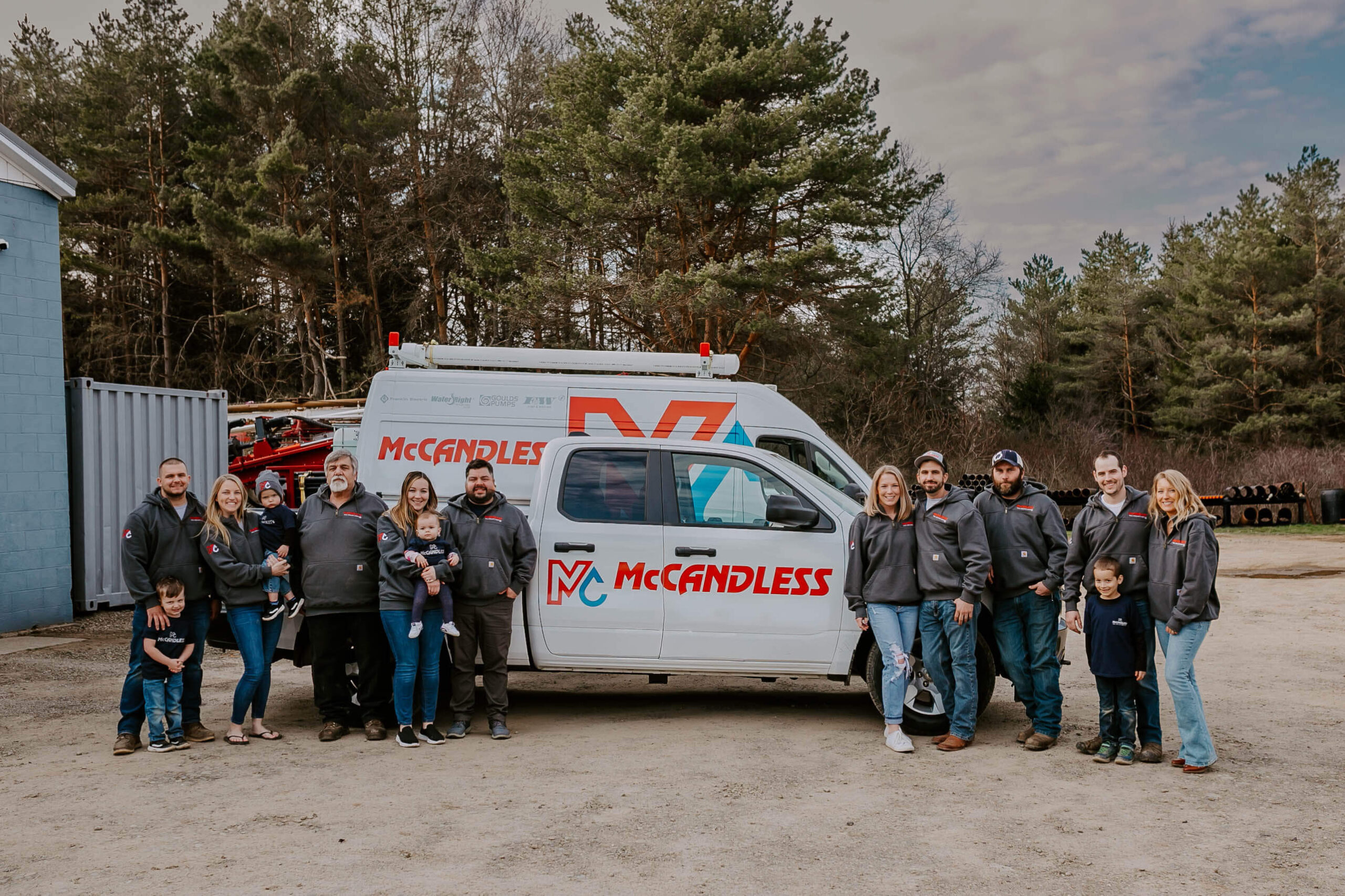 The McCandless Plumbing & Excavation team, adults and kids, smiles together, showing pride in their work and friendly service.