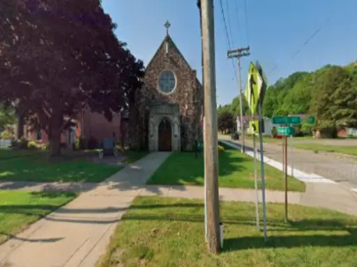 McCandless Plumbing & Excavation offers sewer camera inspections near a church in a sunny, shaded neighborhood setting.