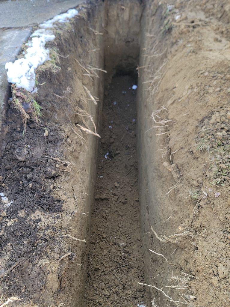 A newly dug trench shows excavation work done by McCandless Plumbing & Excavation, ready for the next construction steps.