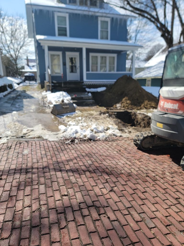 McCandless Plumbing & Excavation is working on a blue house, showing active construction during winter conditions.