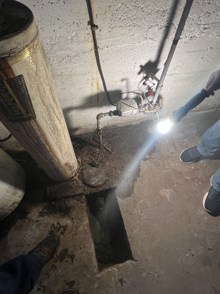 McCandless Plumbing & Excavation inspects a damp, messy spot near a water heater to find the source of a plumbing issue.