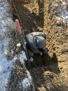 McCandless Plumbing & Excavation team member works in a trench during winter, showing dedication to quality service.