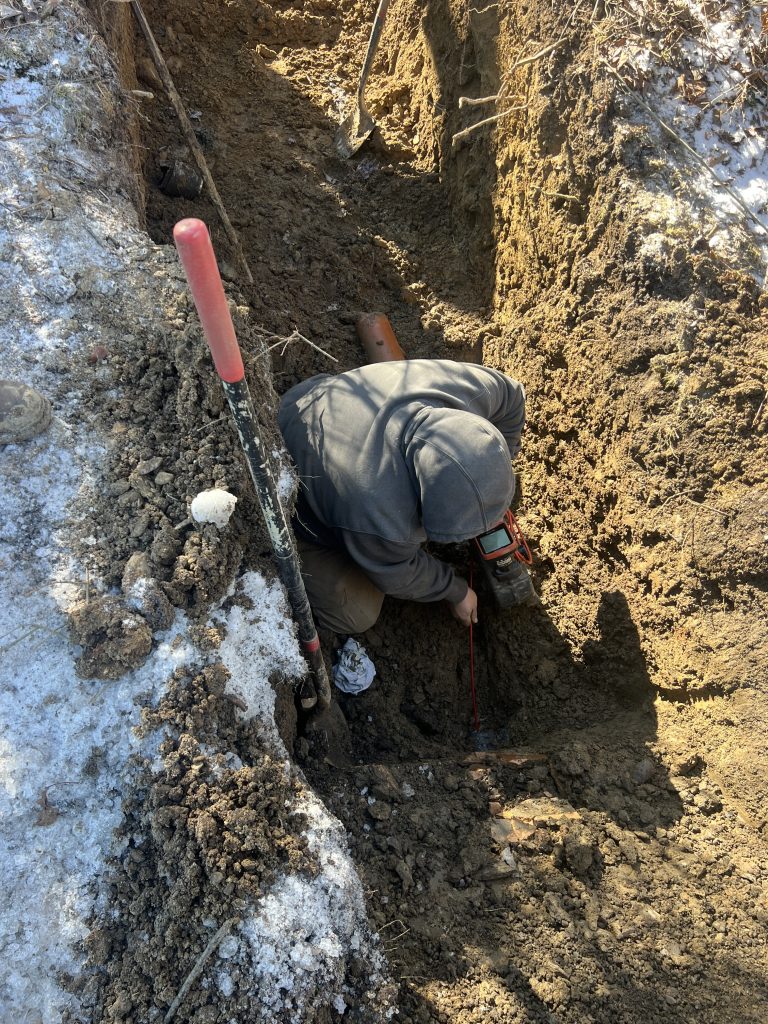 McCandless Plumbing & Excavation team member works in a trench during winter, showing dedication to quality service.