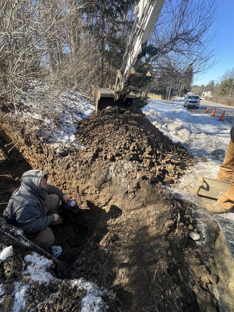 McCandless Plumbing & Excavation crew works by a snowy roadside to repair underground pipes, ensuring safe water flow.