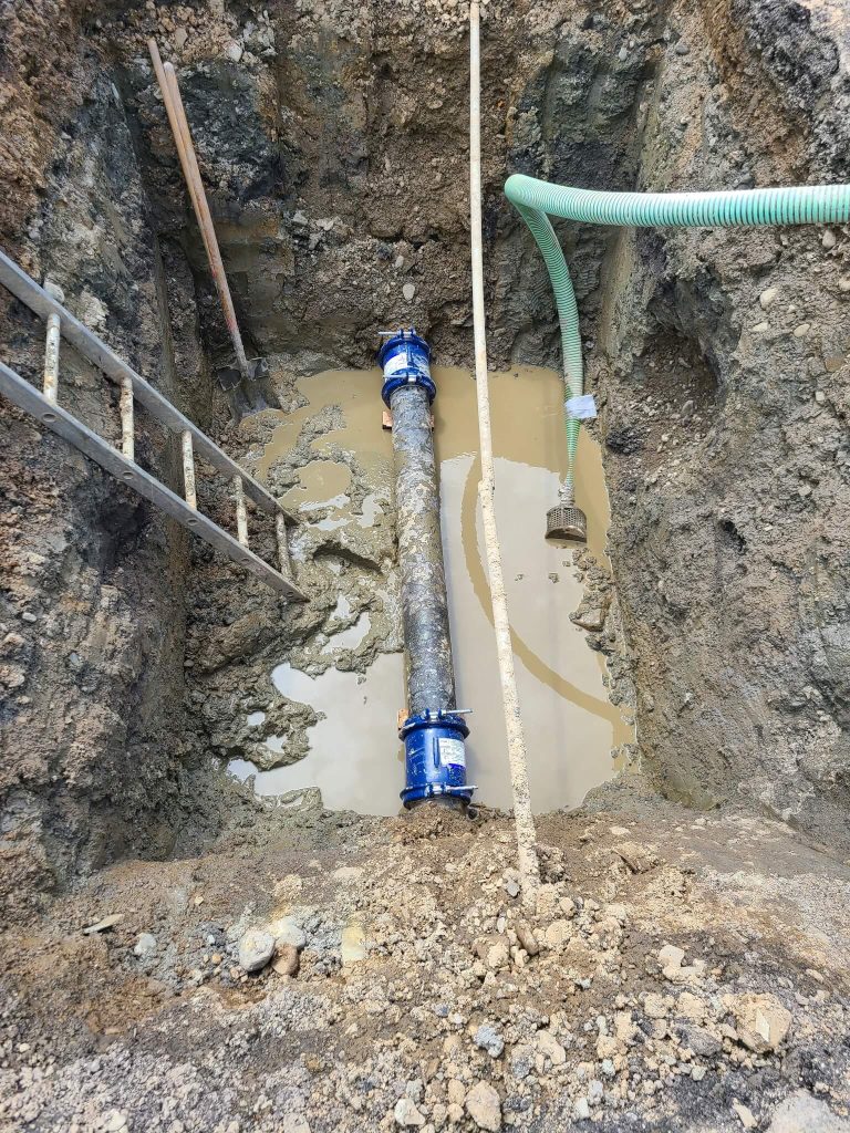 McCandless Plumbing & Excavation installs a pipe in wet soil, showing expertise with drainage and excavation work.
