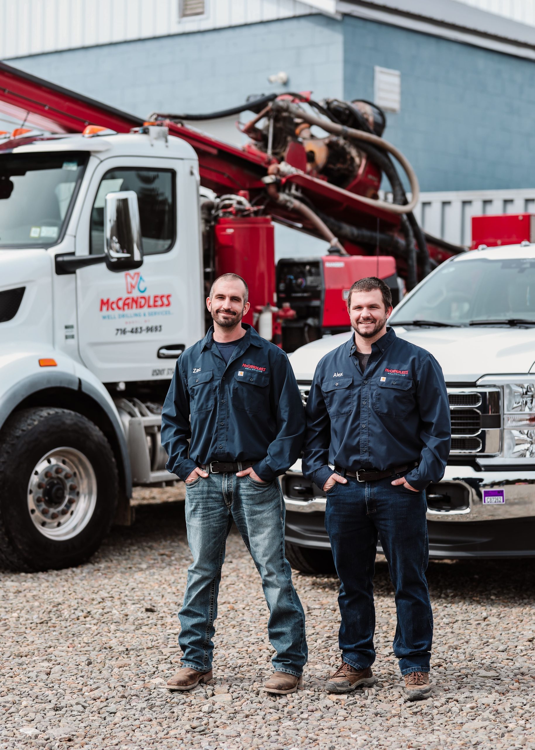 Two smiling workers from McCandless Plumbing & Excavation stand together, showing pride in their company.