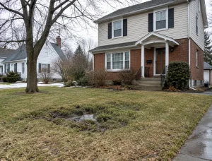 A home with a muddy yard needs help from McCandless Plumbing & Excavation after snow has melted in the area.
