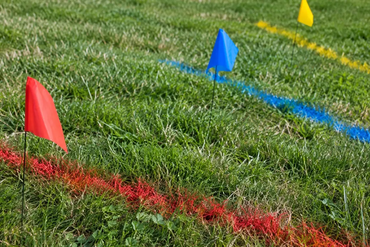 McCandless Plumbing & Excavation marks an outdoor field with colored flags and lines for a planned project or event.